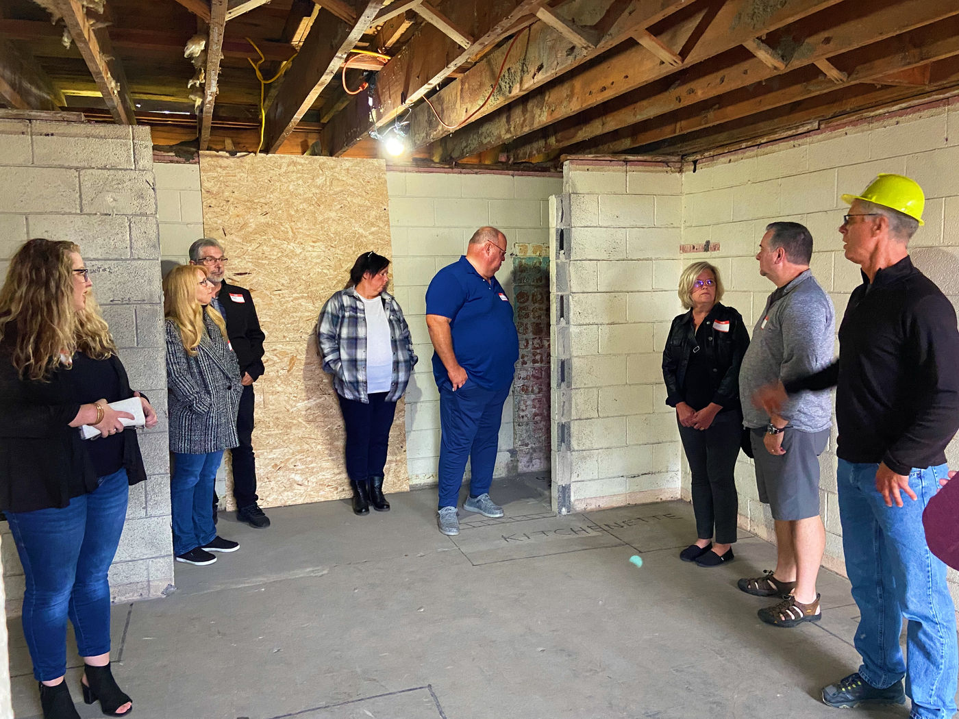 Motel Party guests viewing the contractor's markup of a Bethel Suites bathroom, kitchen, and sleeping area