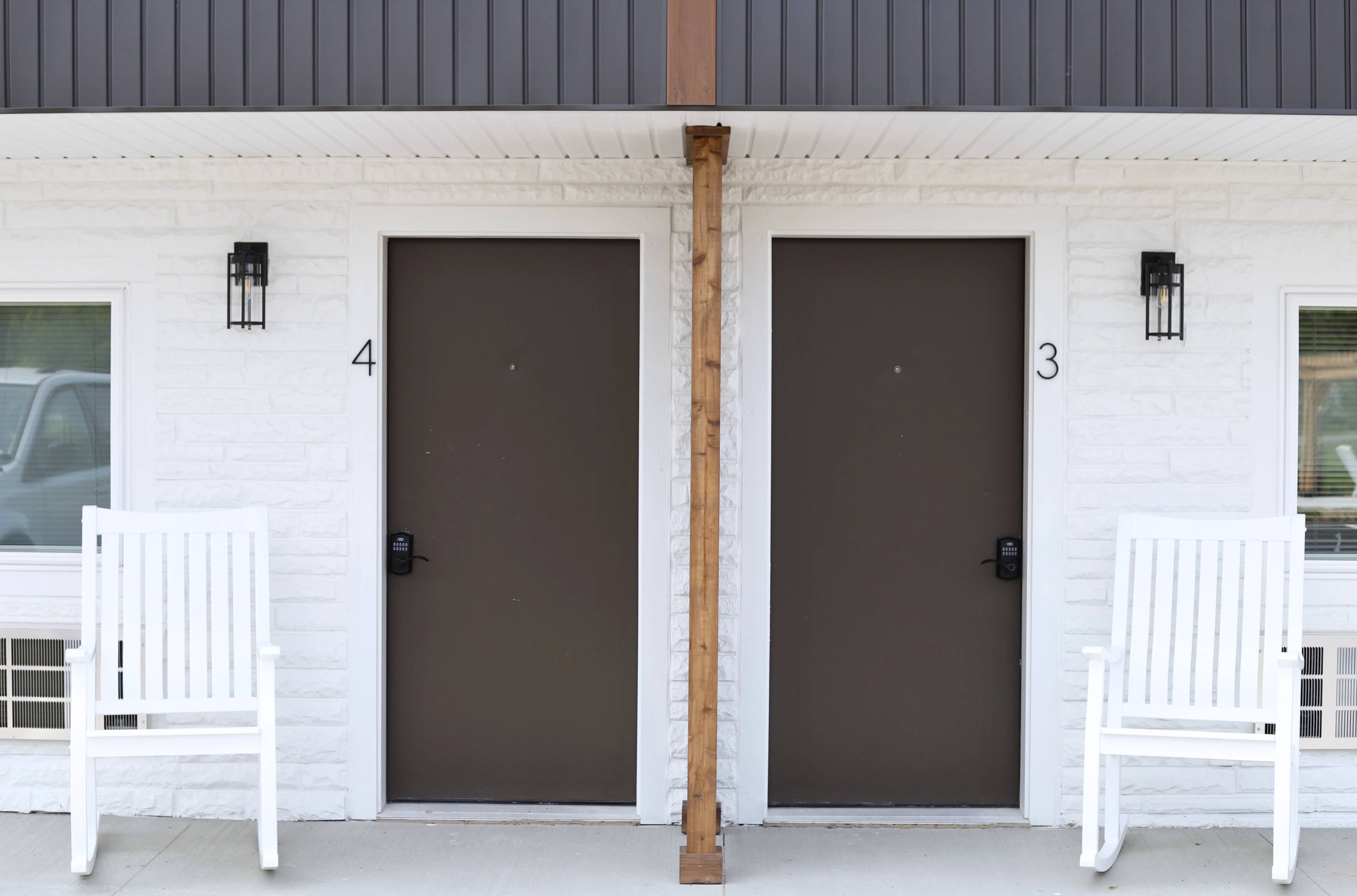 Unit doors with rocking chairs along the renovated exterior