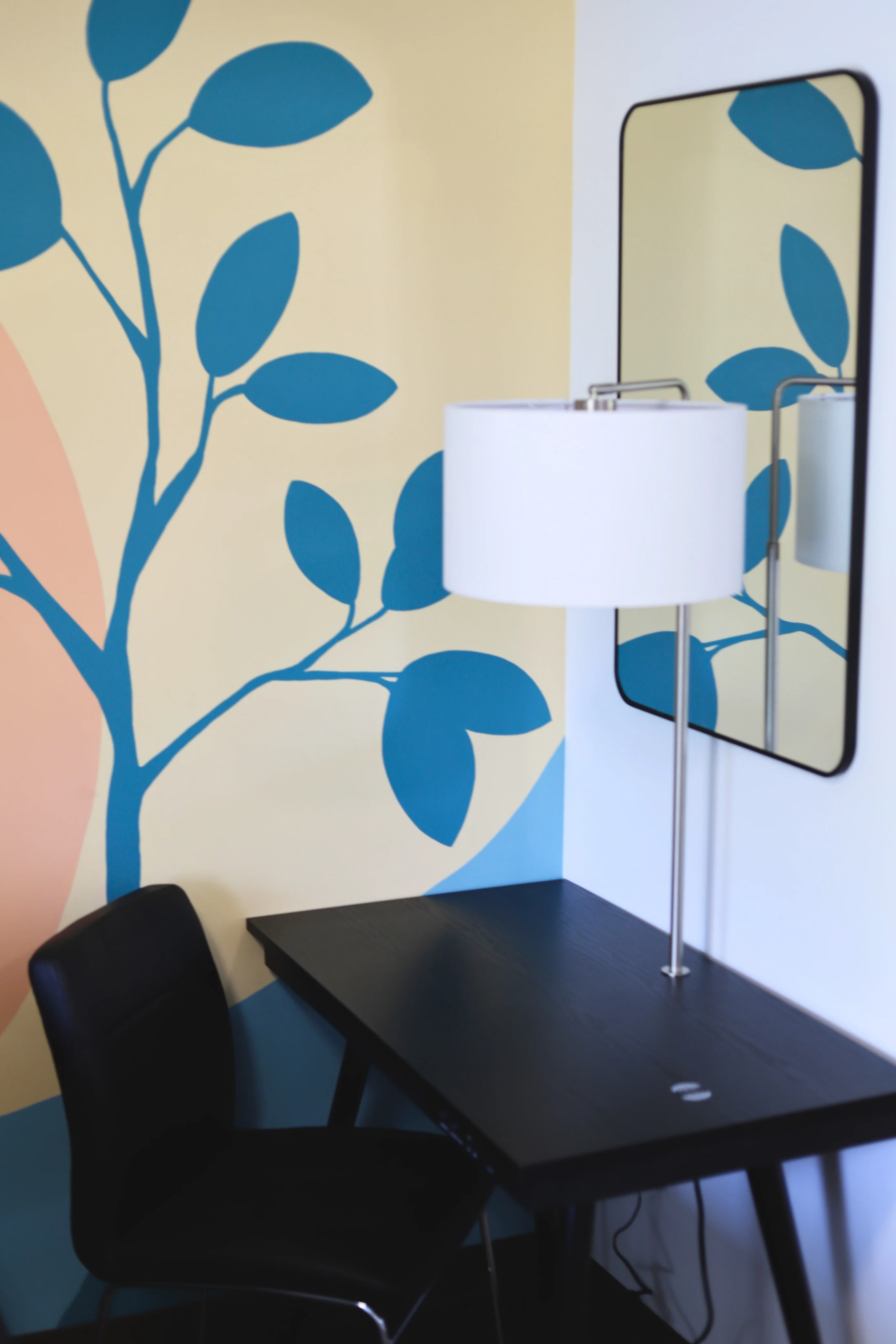 A bright common room with a hand-painted leaf mural